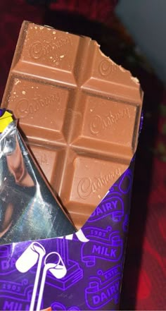 a bar of chocolate sitting on top of a purple and white wrapper next to it's wrapper