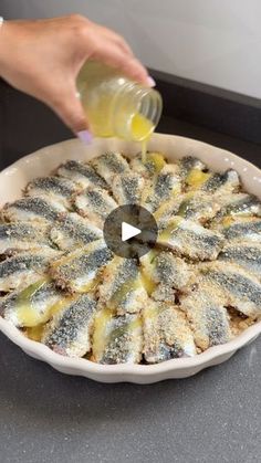 someone is pouring something into a dish with lemons in it and on the side