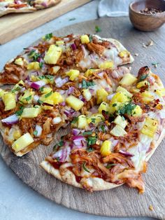 two pizzas with pineapple, onions and other toppings on wooden cutting boards