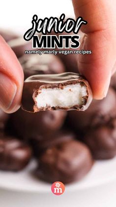 a hand holding a piece of chocolate covered with marshmallows on top of a white plate