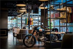 a motorcycle parked inside of a store filled with lots of furniture and lighting hanging from the ceiling