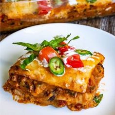 a white plate topped with lasagna covered in cheese and veggie toppings