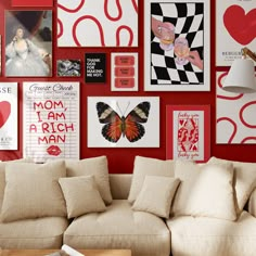 a living room filled with lots of red and white wall art above a couch covered in pillows