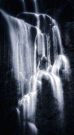 a black and white photo of water cascading from the top of a waterfall