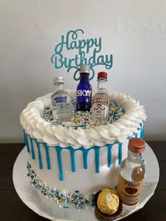 a birthday cake with frosting and confetti on it, surrounded by liquor bottles