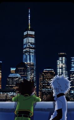 two people standing in front of a city at night