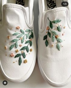 white shoes with embroidered flowers and leaves on the side, sitting on top of a table