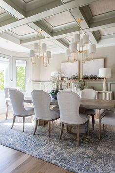 a dining room table with white chairs and chandelier hanging from the ceiling above it