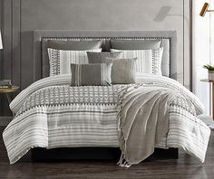 a bed with white and grey comforters in a room