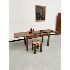 a wooden table with two stools next to it and a painting on the wall