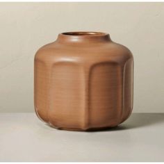 a brown vase sitting on top of a white table