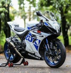 a white and blue motorcycle parked on the side of a road in front of trees