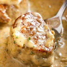 two meatballs covered in gravy with a spoon sticking out of the top