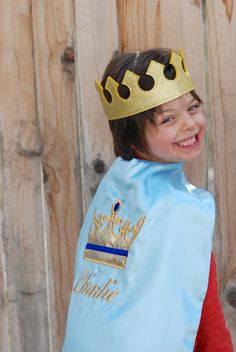 a young boy wearing a blue vest with a gold crown on it's head