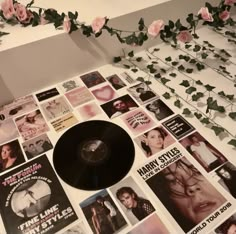 a record sitting on top of a table covered in pictures and flowers next to a plant