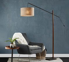 a living room with blue walls and a gray chair next to a lamp on a table