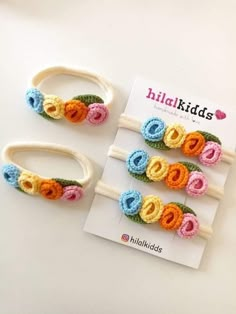 four crocheted hair clips with flowers on them sitting next to a book that says hilakids