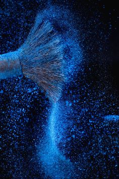 blue powder is being thrown into the air with a broom on it's head