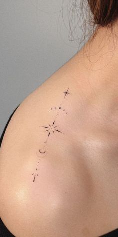 the back of a woman's shoulder with a cross and stars tattoo on it