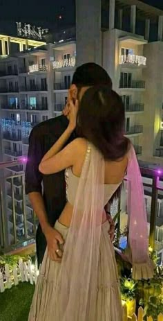 a man and woman standing next to each other on top of a balcony at night