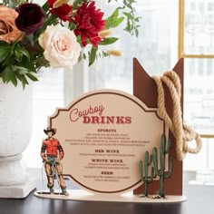 a cowboy themed drink menu on a table next to a vase with flowers in it