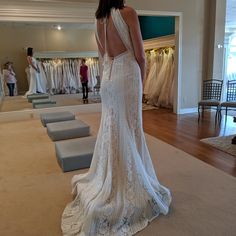 a woman in a wedding dress looking down at the floor with dresses on display behind her