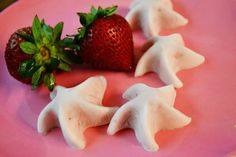 strawberries and marshmallows sit on a pink plate with white icing