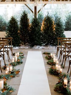 the aisle is decorated with candles and greenery for an outdoor wedding ceremony in winter