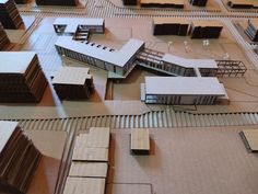 a model train station with several buildings on the tracks and one building is made out of cardboard