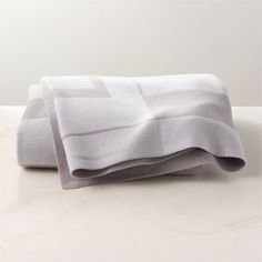 two folded towels sitting on top of a table next to each other with white and gray stripes