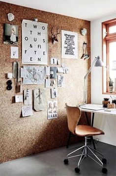 a desk with a chair in front of a cork board wall covered in pictures and letters