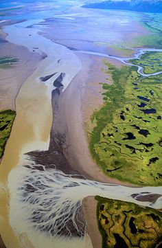 an aerial view of the ocean and land from above, with water running through it