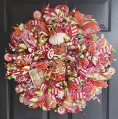 a christmas wreath hanging on the front door decorated with candy canes, candies and a gingerbread man