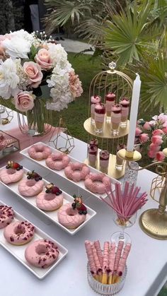 a table topped with pink donuts covered in frosting and surrounded by other desserts