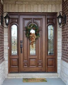 the front door is decorated for christmas with wreaths on it and two sidelights