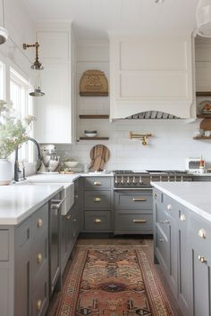 a kitchen with gray cabinets and white counter tops, an area rug on the floor