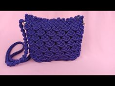 a purple crocheted purse sitting on top of a pink surface