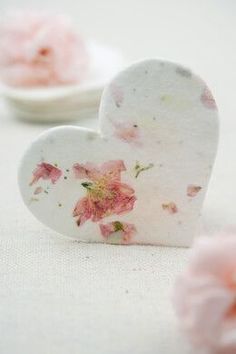 two small white heart shaped dishes with pink flowers on the top and one in the middle