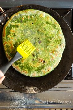 a pancake being cooked in a skillet with a yellow spatula on top