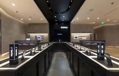 an empty restaurant with black counters and white counter tops, along with the samsung logo on the wall