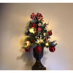 a christmas tree with ornaments and lights in a vase