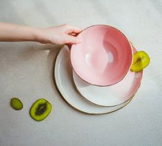 a person holding a pink bowl with kiwi slices on the side next to it