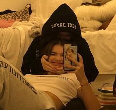 a woman taking a selfie with her cell phone in front of her face while sitting on a bed