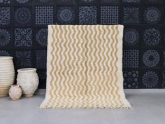 a white and brown rug sitting on top of a floor next to vases