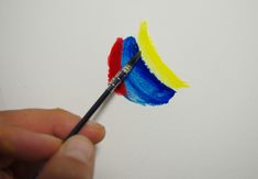 a person is holding a paintbrush and painting on a white wall with bright colors