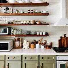 a kitchen with open shelving above the stove and shelves filled with dishes, mugs, utensils and other items