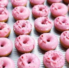 pink frosted doughnuts with sprinkles are on a baking sheet