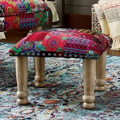 a colorful bench and foot stool in a living room with rugs on the floor