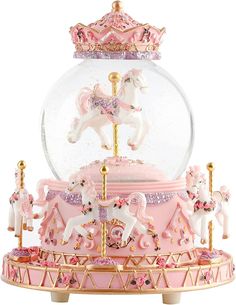 a pink carousel with white horses and gold trimmings in a glass ball on top