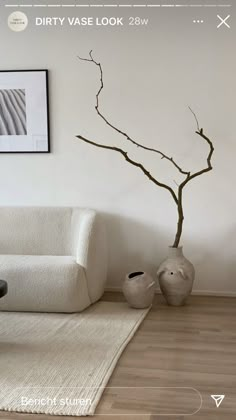 a white couch sitting next to a vase on top of a wooden floor